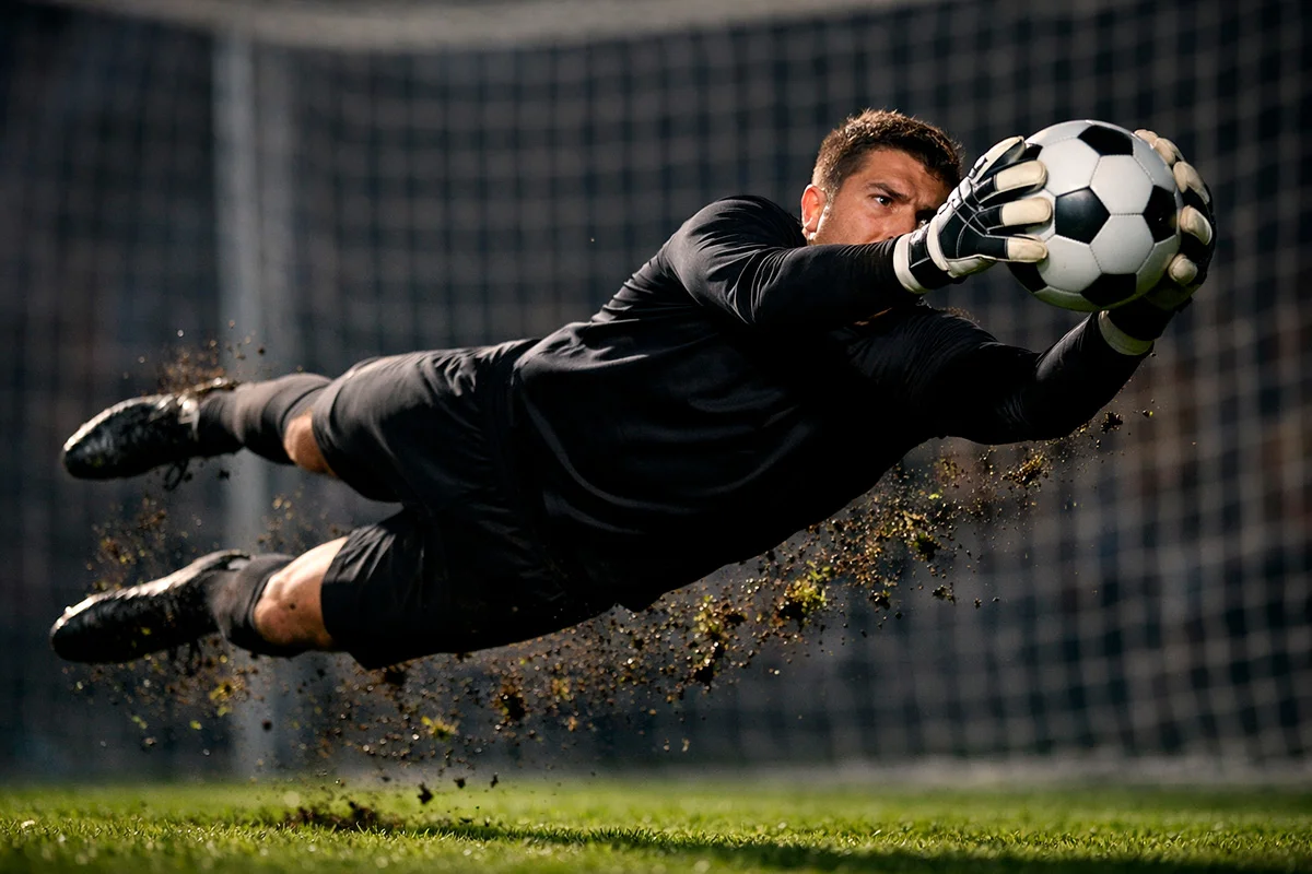 Portiere di calcio che para un tiro in tuffo spettacolare su campo in erba