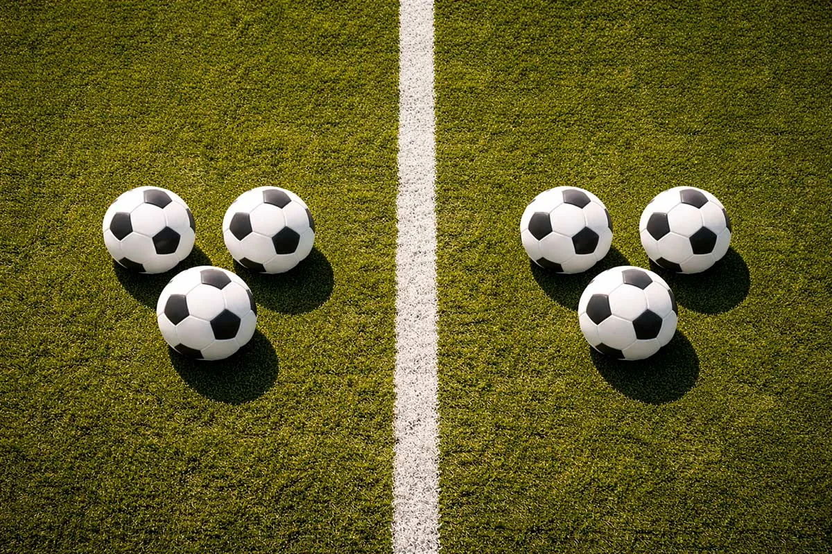 Due gruppi di tre palloni da calcio separati da una linea bianca sul campo verde