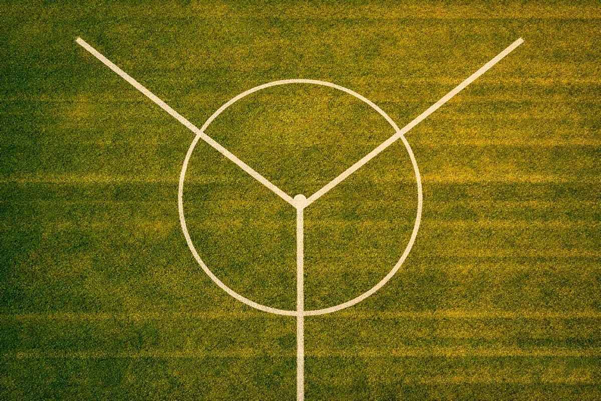 Due strade divergenti su un campo di calcio viste dall'alto al tramonto